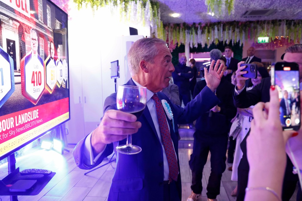 a man holds a glass of wine in front of a screen that says our landslide