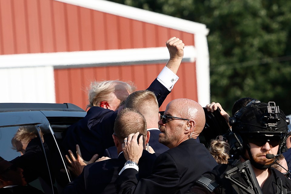 Trump pounds the air with a fist as he's bundled into a car and whisked away