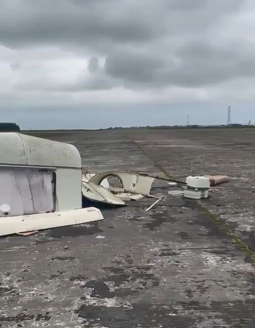 a broken caravan is sitting on the ground in a field .