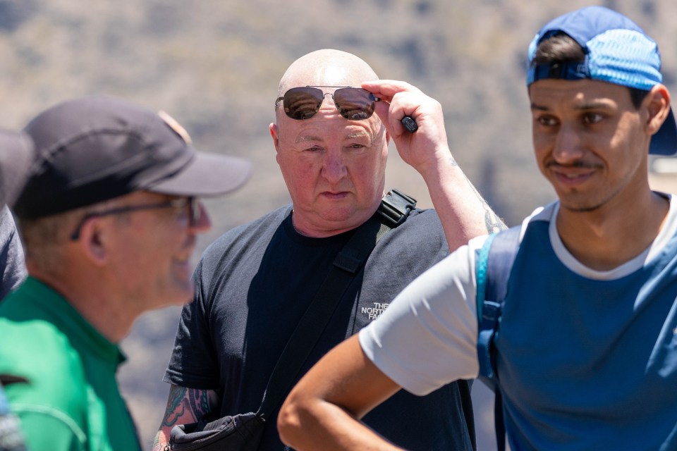 a man wearing a north face shirt adjusts his sunglasses