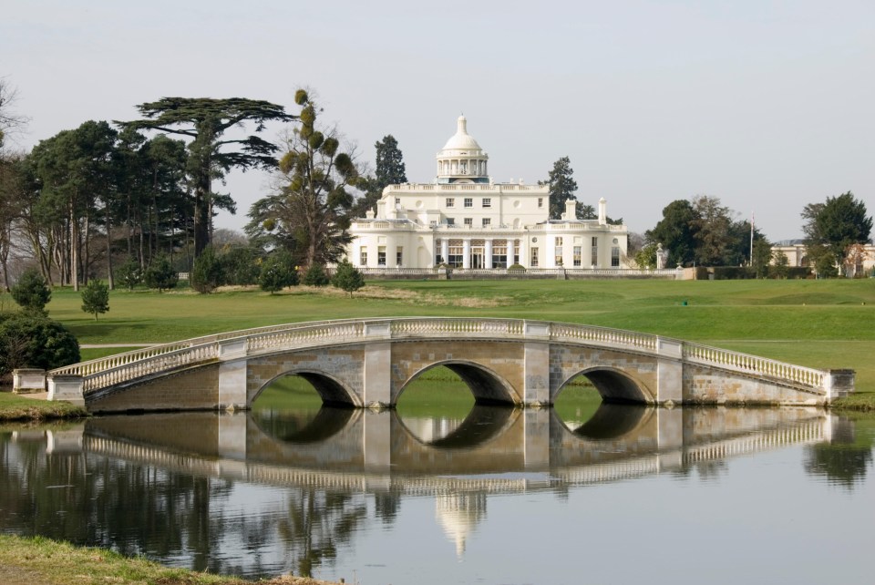 a bridge over a body of water with a large white building in the background