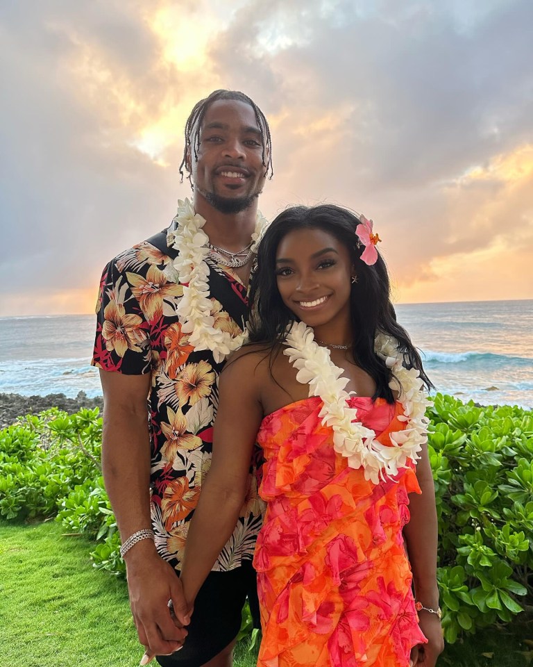 a man and a woman are posing for a picture in front of the ocean