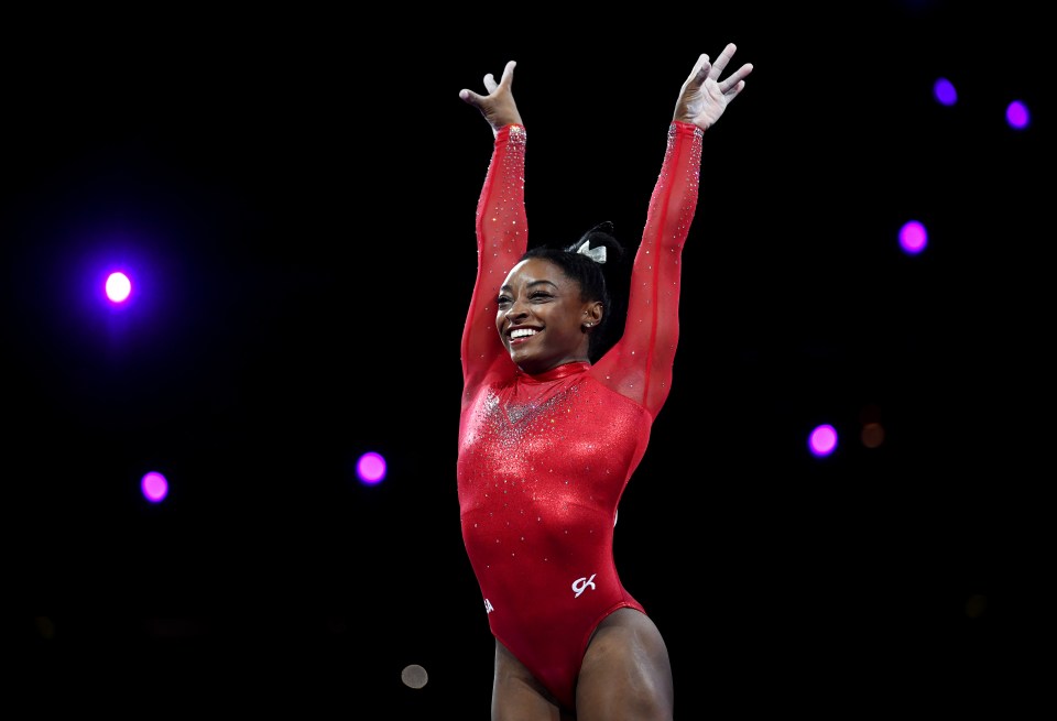 a gymnast wearing a red leotard with the letter g on it