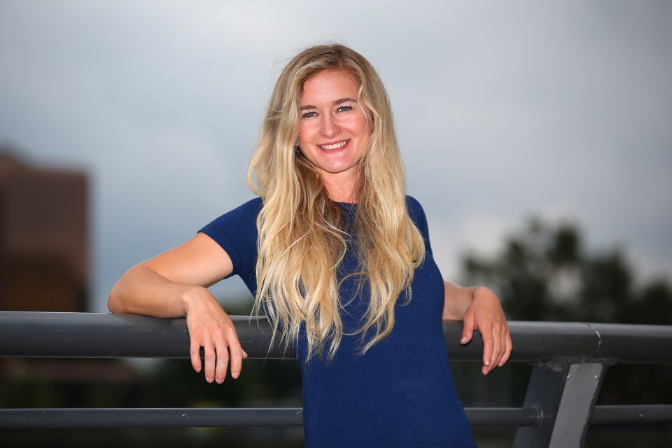 a woman in a blue shirt leans on a railing