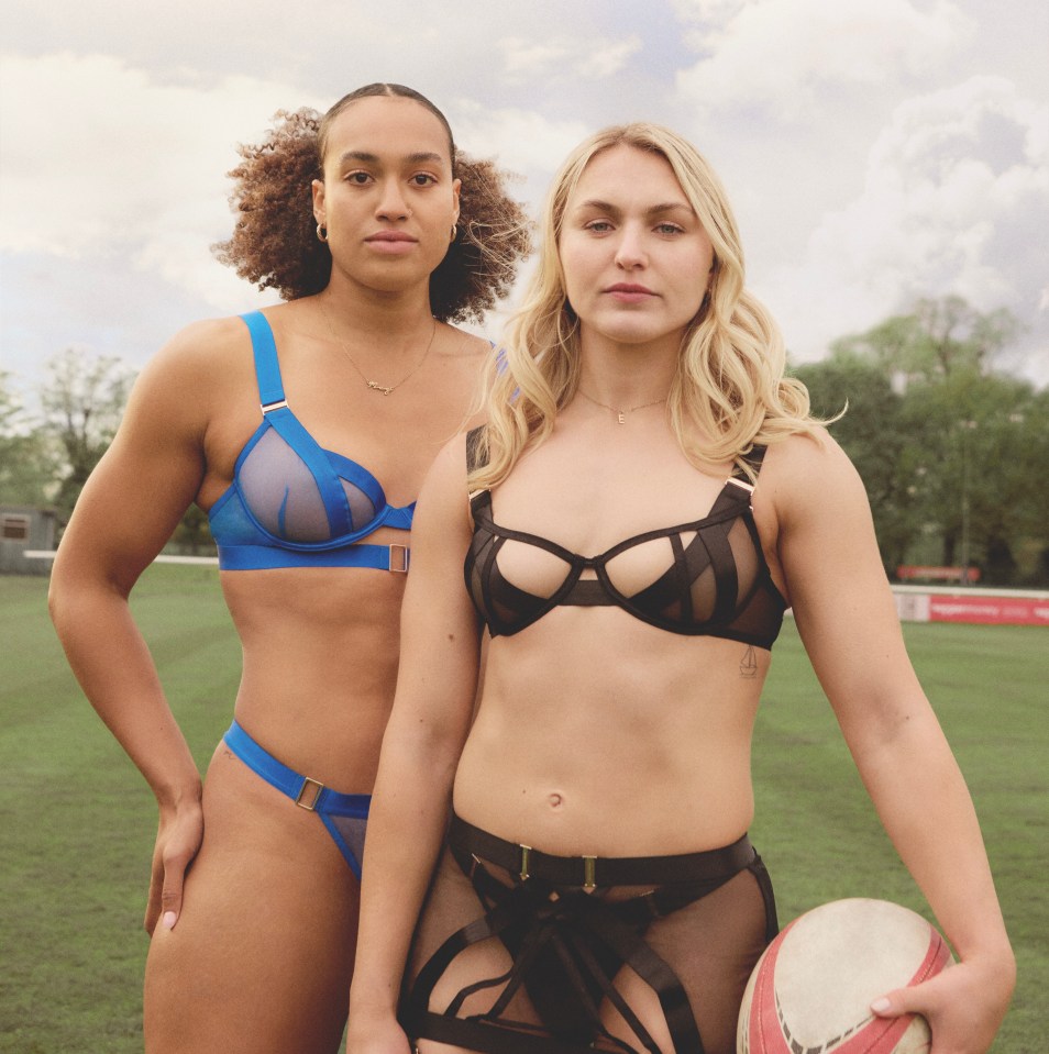 two women in lingerie pose for a picture on a field