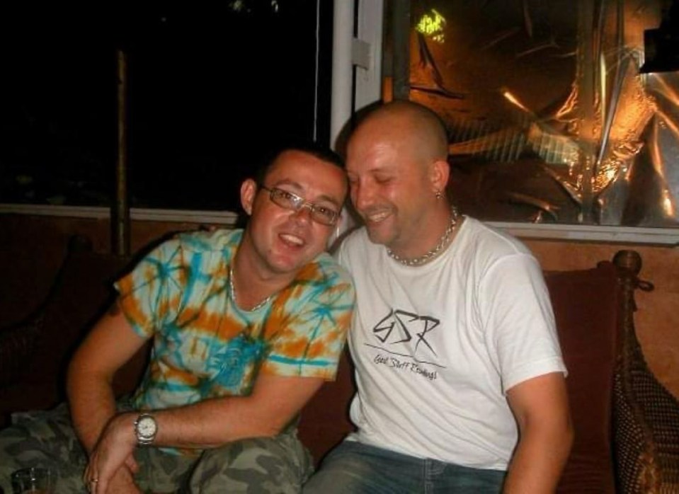 two men are sitting next to each other on a couch and smiling .