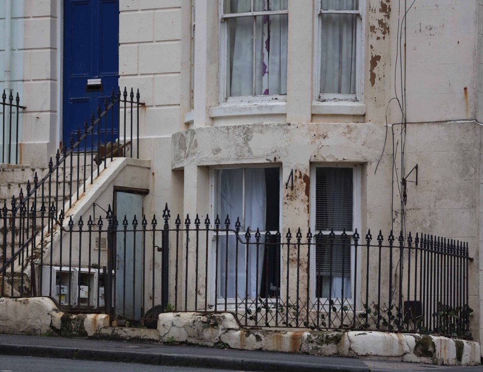 a white house with a blue door and a black fence