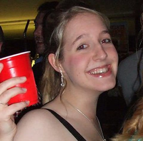 a woman is holding a red solo cup and smiling .