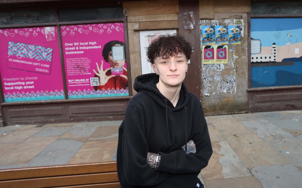 a young man stands in front of a scarborough gift card advertisement