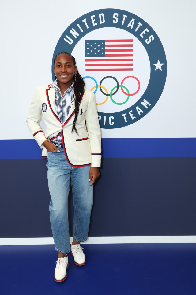 a woman stands in front of a united states olympic team logo