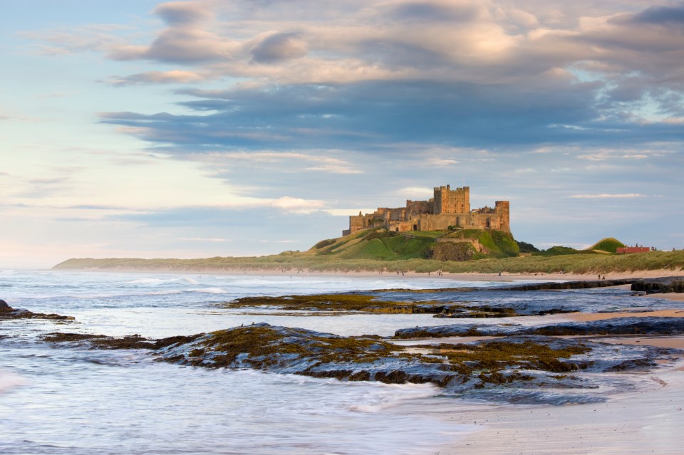 Bamburgh Castle stands imposingly atop a hill behind the beach