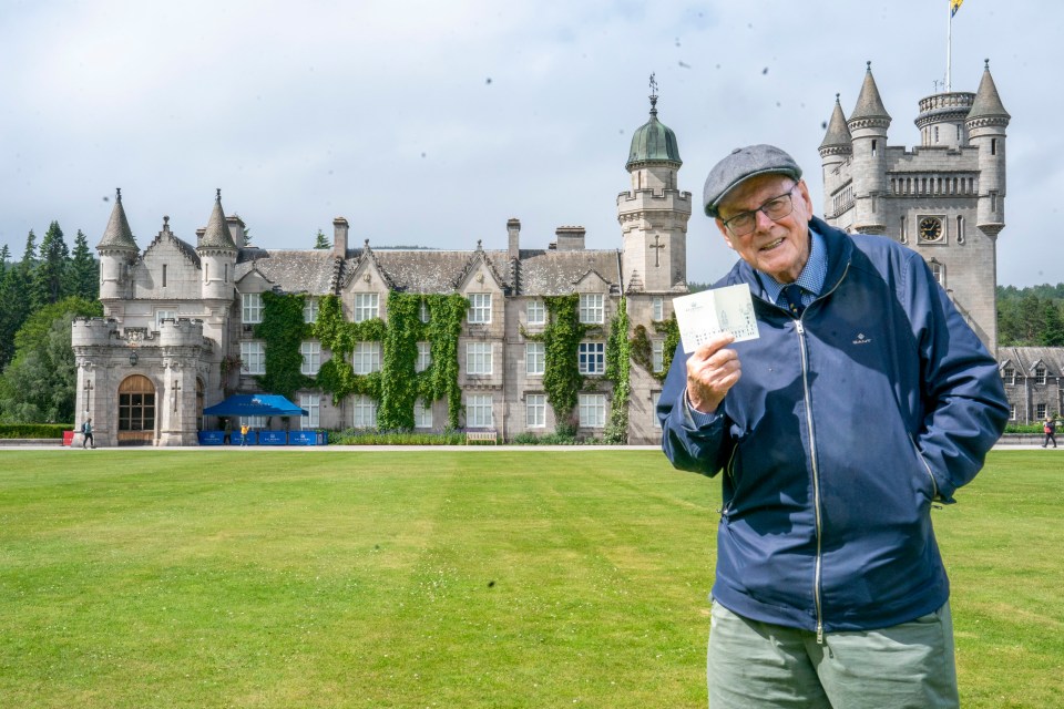 a man holding a ticket in front of a castle