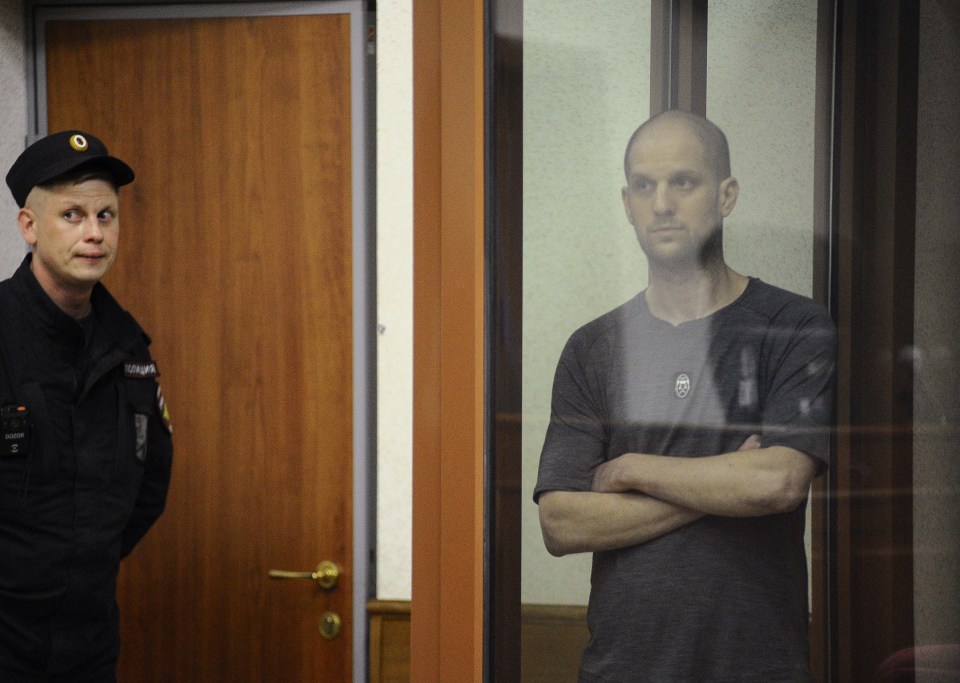 a man wearing a black shirt with a logo on it stands next to a police officer