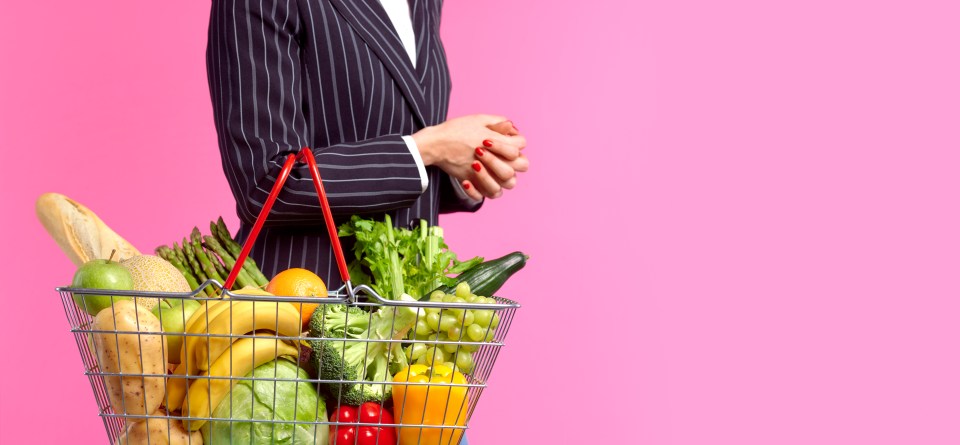 Woman holding a shopping basket full of vegetables and fruit