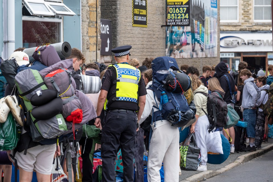 a police officer stands in front of a crowd of backpackers