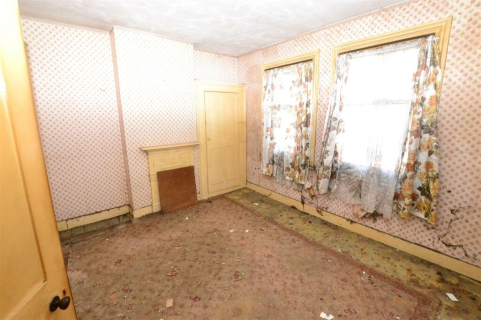 an empty room with a fireplace and floral curtains