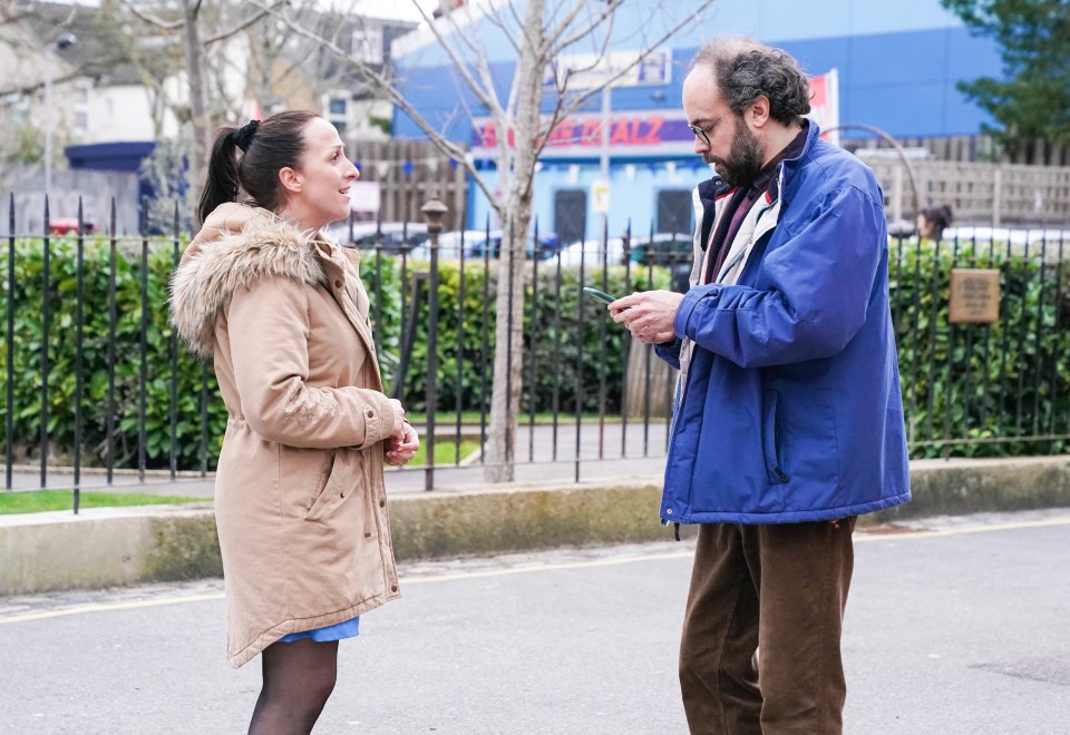 a man in a blue jacket talks to a woman in a parka