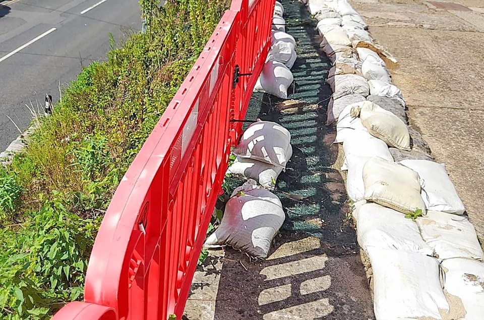 a red fence surrounds a row of sandbags