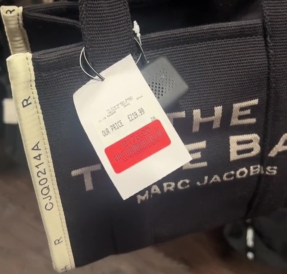 a person is holding a black marc jacobs tote bag