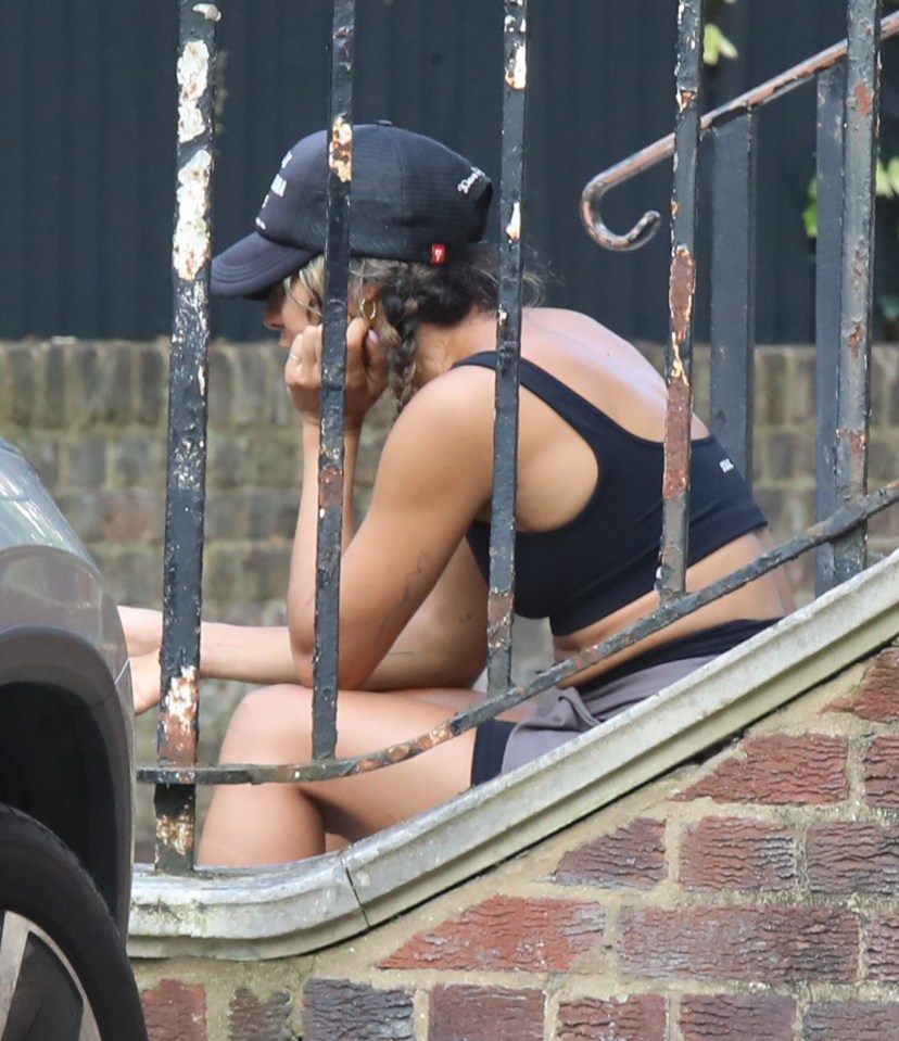 a woman sits on a set of stairs wearing a hat that says reebok