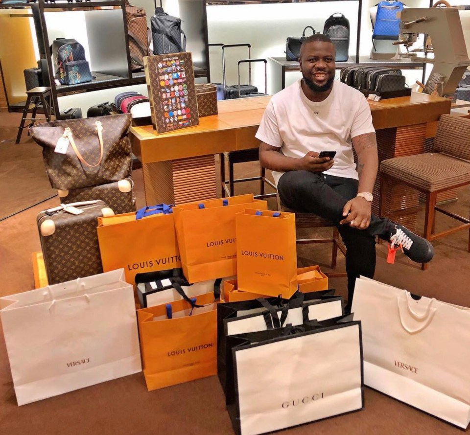 a man sits in a store surrounded by louis vuitton bags