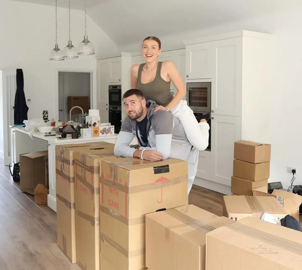 a woman is sitting on a man 's shoulders in a kitchen surrounded by moving boxes