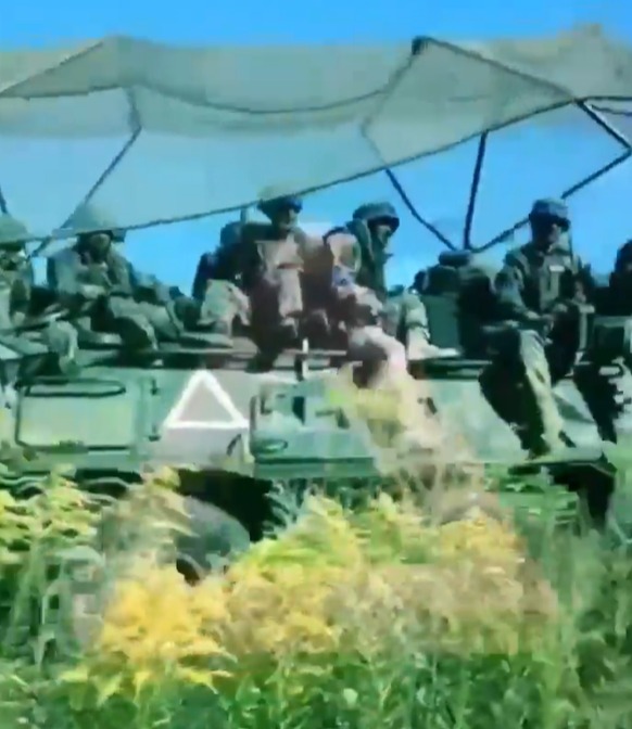 a group of soldiers are sitting on top of a military vehicle with the letter a on it