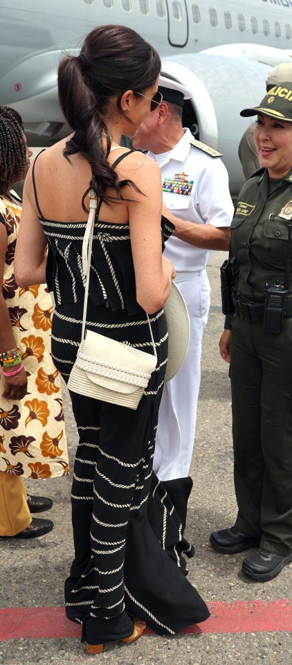 a woman in a black and white dress stands next to a police officer