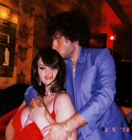 a man in a blue suit is hugging a woman in a red bra .