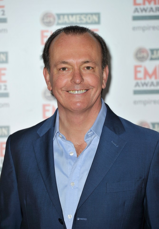 a man in a blue suit smiles in front of a jameson sign