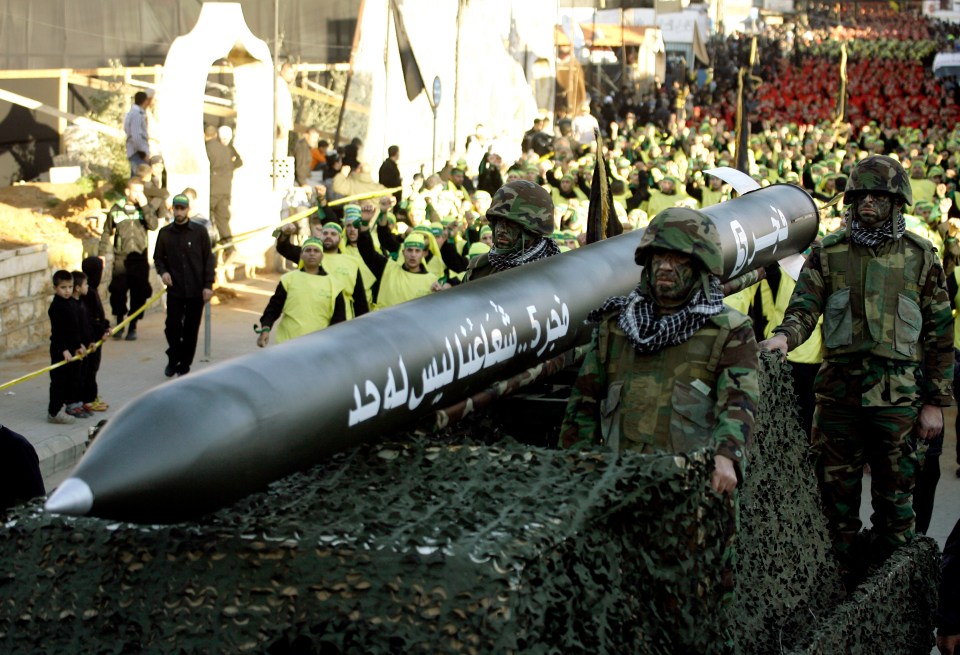 a group of soldiers carrying a large rocket with arabic writing on it