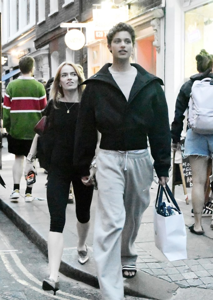 a man and a woman walking down a street with a sign that says ' on 7 ' on it