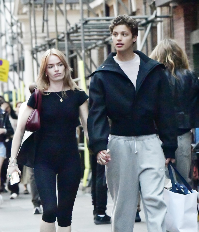 a man and a woman walking down a street holding hands