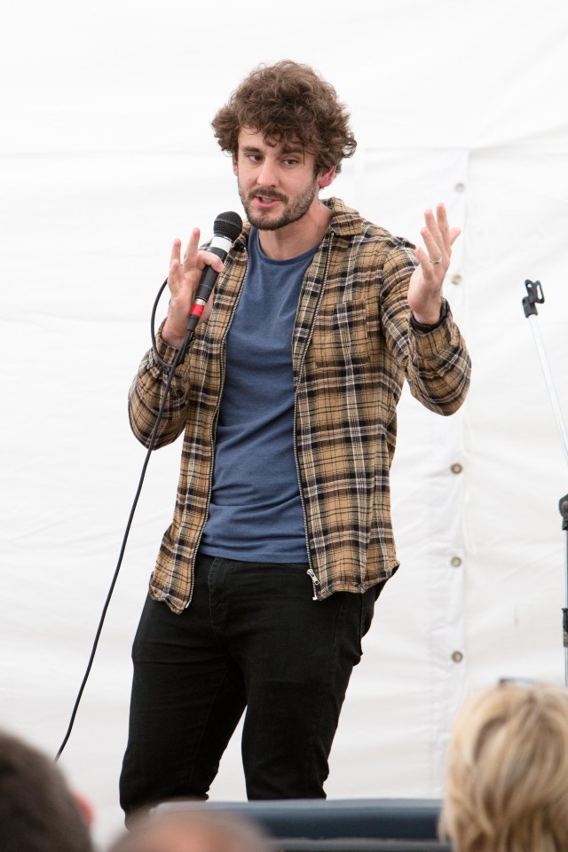 a man in a plaid shirt is speaking into a microphone