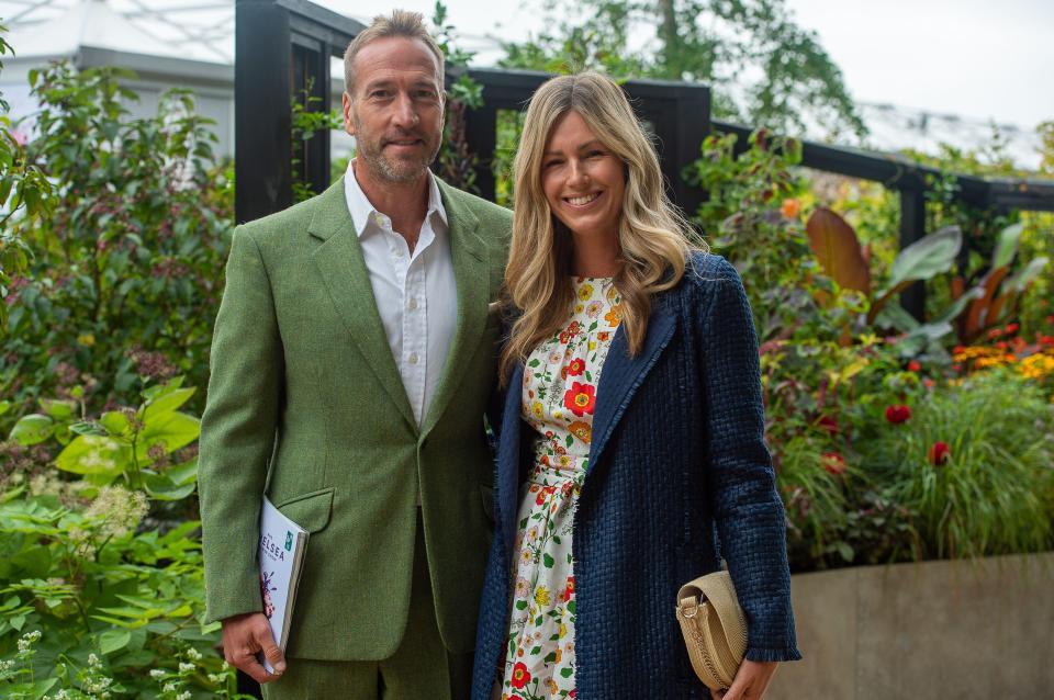 a man in a green suit stands next to a woman in a floral dress