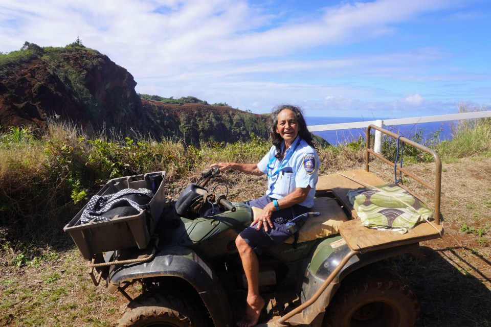 a man sitting on a four wheeler with a hawaiian badge on his shirt