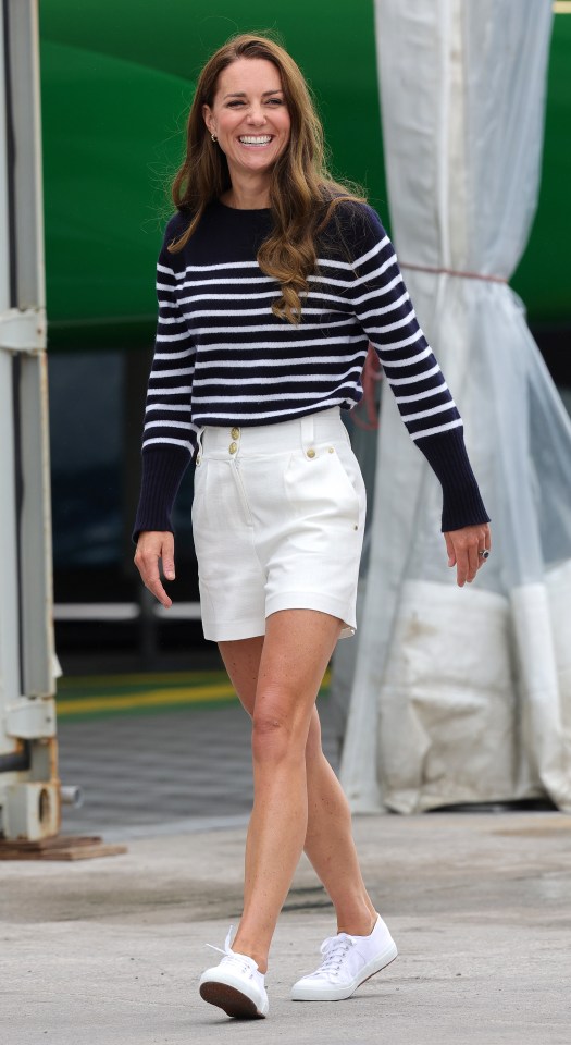 a woman wearing a striped sweater and white shorts is smiling