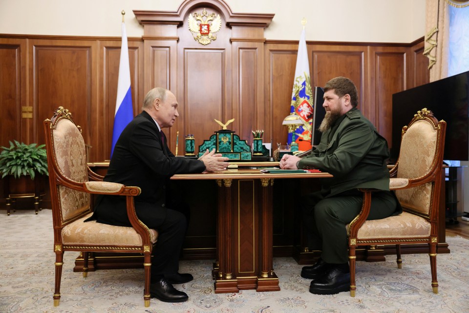 two men are sitting at a table with flags in the background