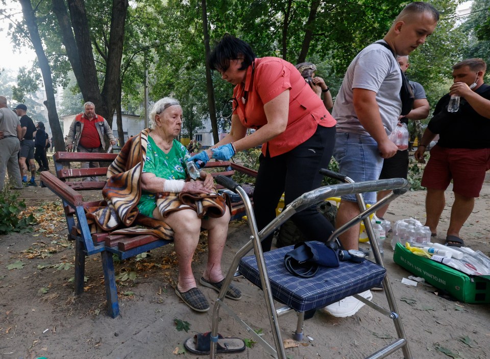 a woman in a red shirt is helping an elderly woman with a walker