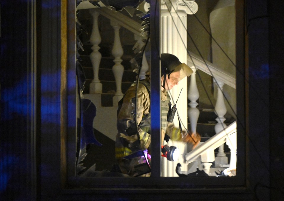 a fireman stands in front of a staircase with a broken window