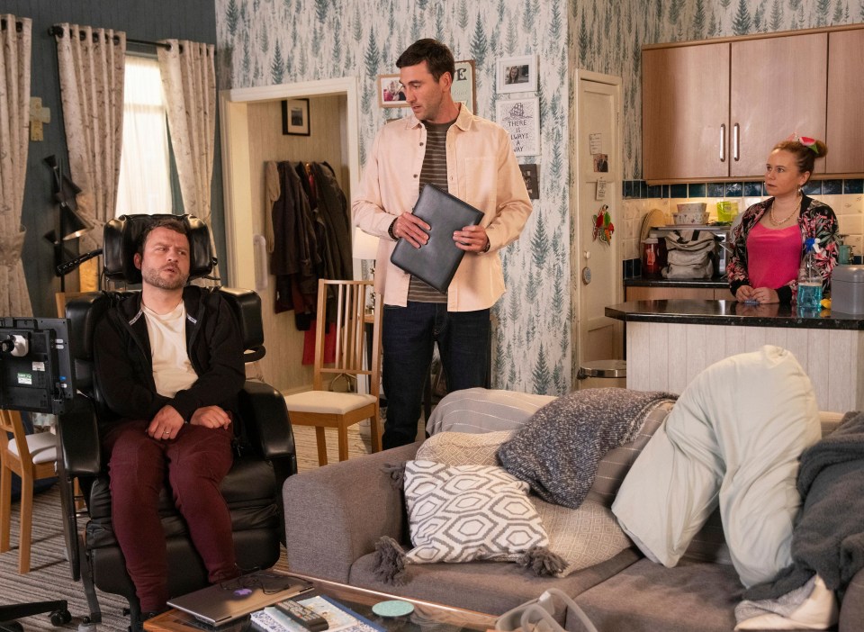 a man in a wheelchair sits in a living room with two other people