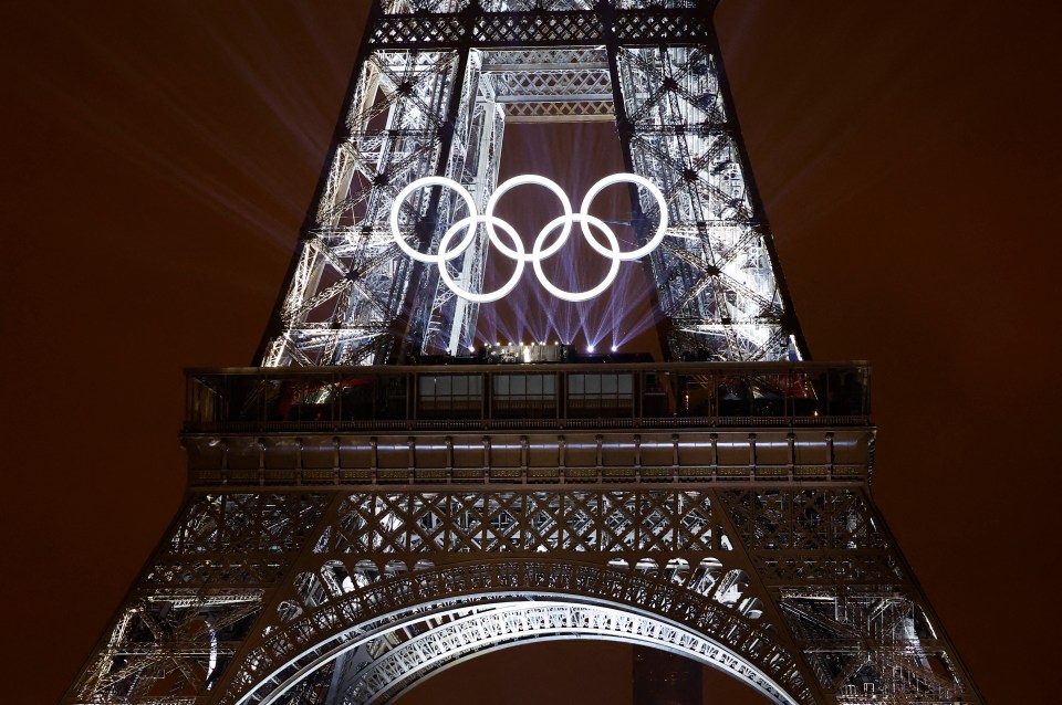 the olympic rings are projected on the eiffel tower