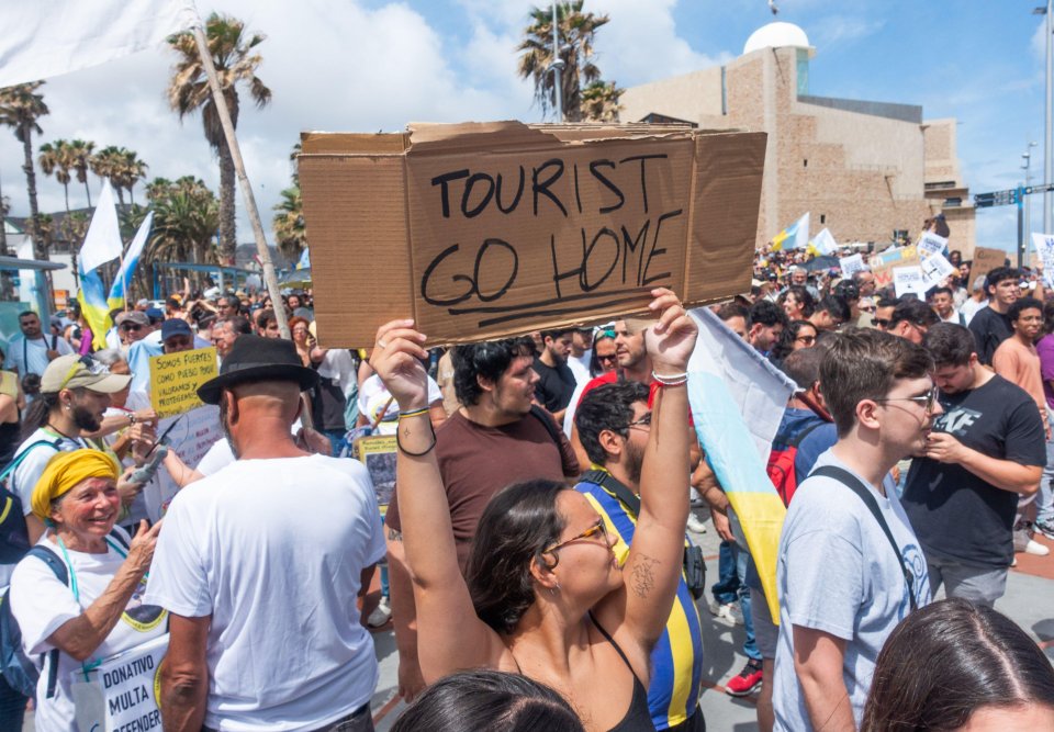 a woman holds up a sign that says tourist go home