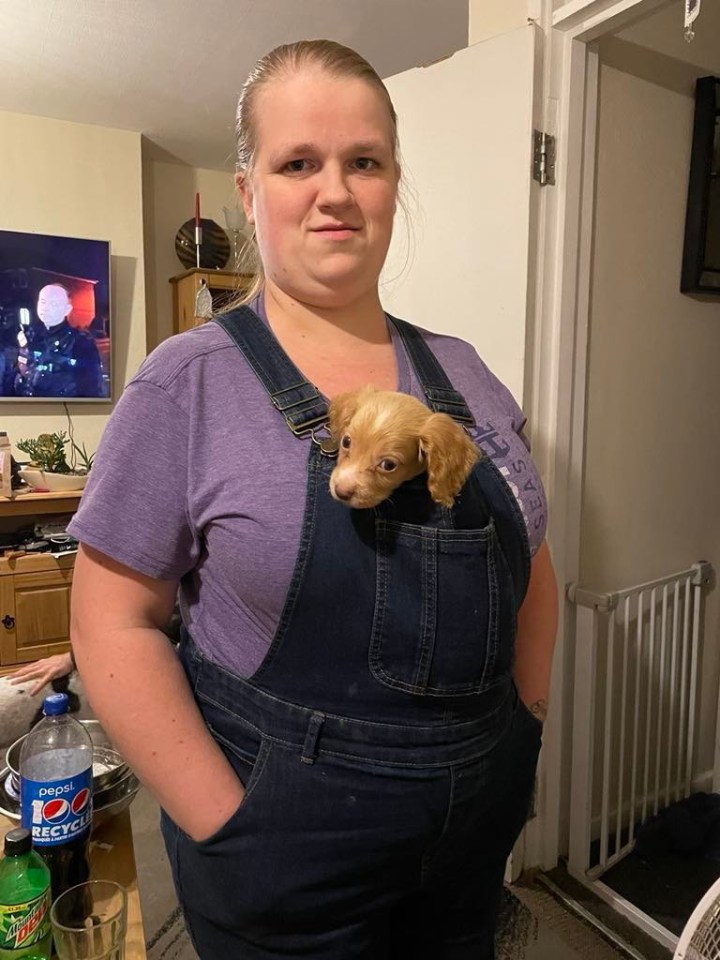 a woman wearing overalls holds a puppy in her pocket next to a mountain dew bottle