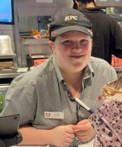 a woman wearing a kfc hat is sitting at a counter in a restaurant .