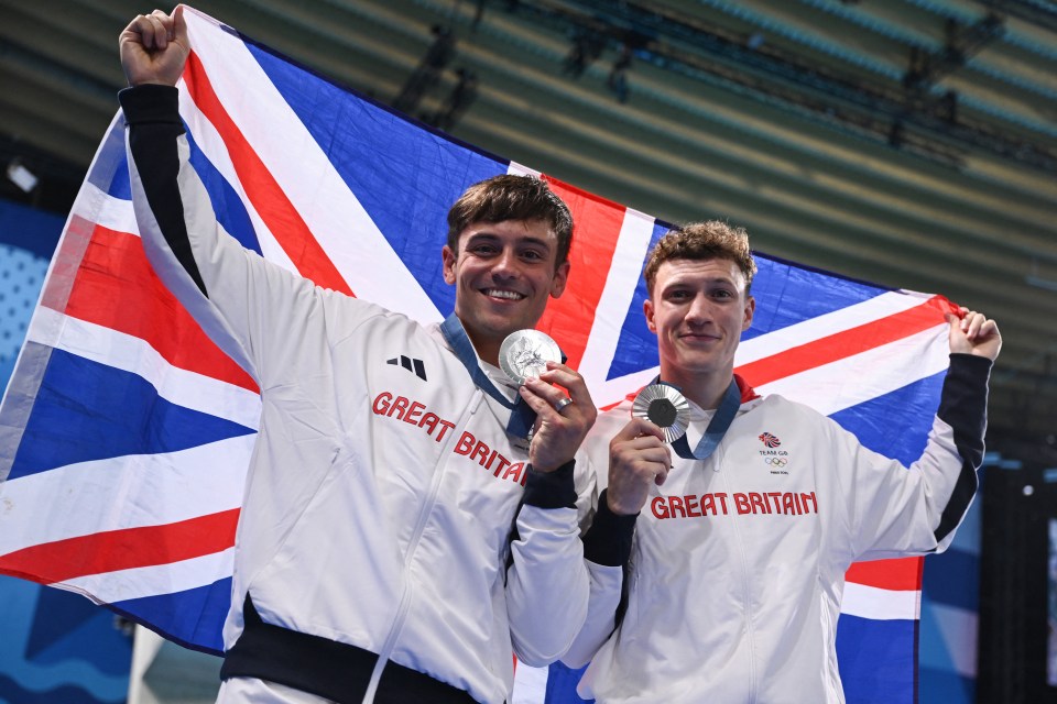 two great britain athletes holding a flag and medals