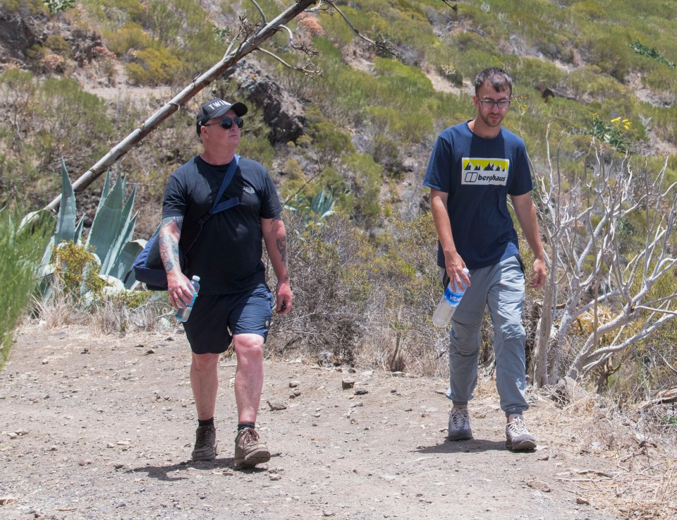 a man wearing a blue shirt that says berghaus walks with another man