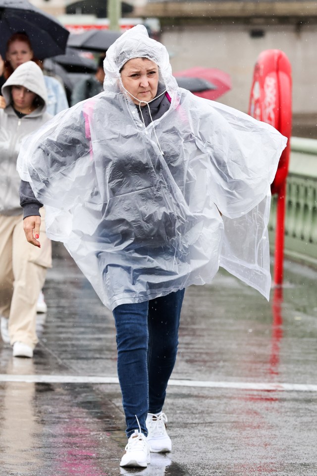 a woman wearing a clear plastic poncho is walking in the rain