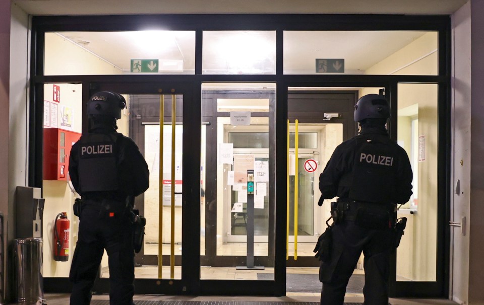 Two officers stand guard in front of a refugee centre during a police search in Solingen