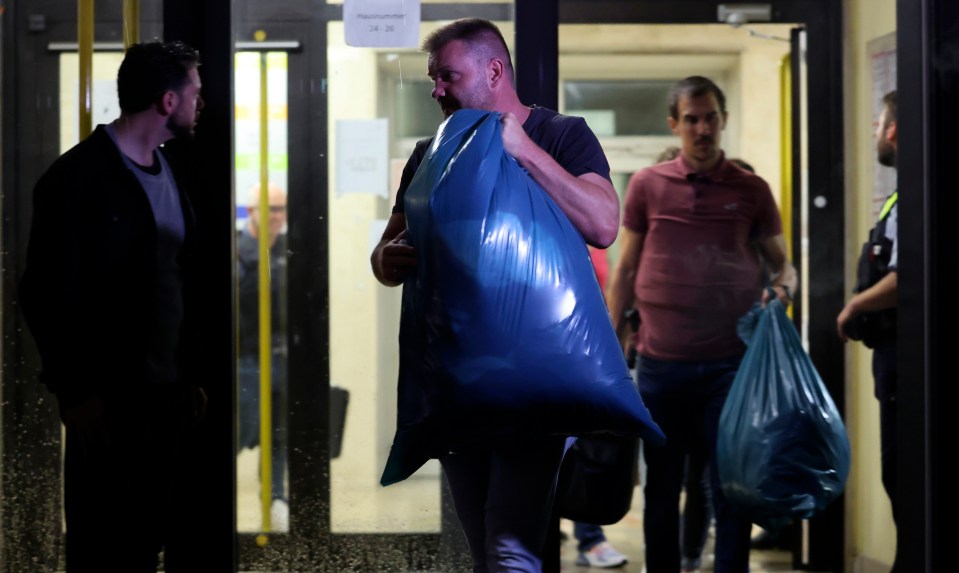 a man is carrying a large blue bag in front of a sign that says " garderobe "